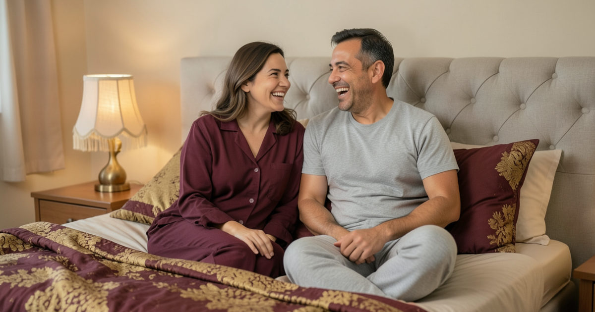 Casal vestido conversando e rindo na cama, em luz suave